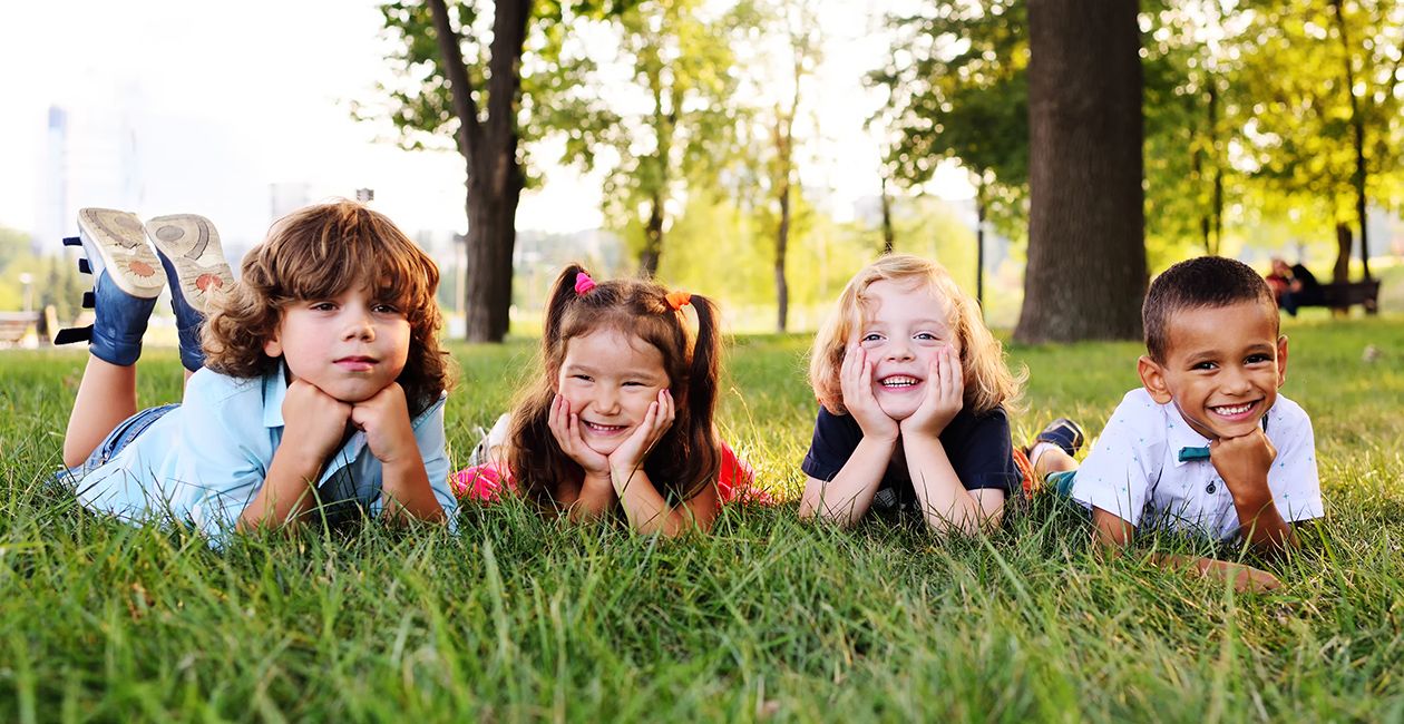 group of kids lying down on their stomachs in the Park on the grass