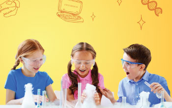 2 girls and a boy laughing and playing with test tubes. smoke coming out of 3 beakers