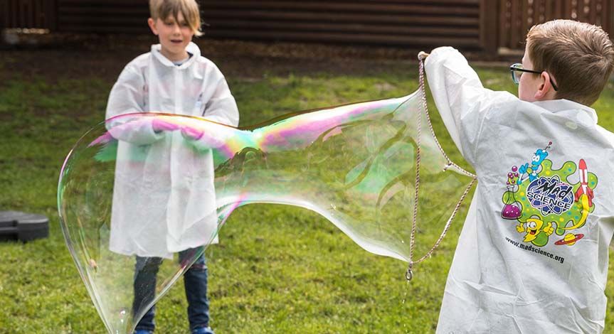 2 boys in mad science lab coats playing with a bubble