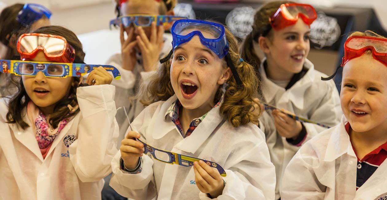 a group of amazed kids wearing diffraction glasses