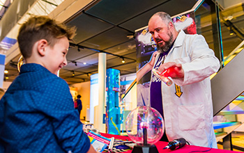 Mad scientist holding red light in from of boy.