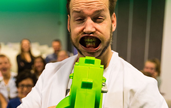 Mad scientist using a green air blower, blowing his mouth wide open