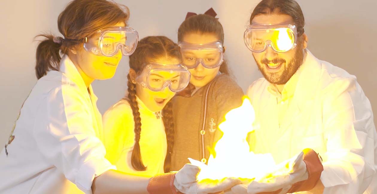 Kids and mad scientists wearing safety goggles looking at paper on fire