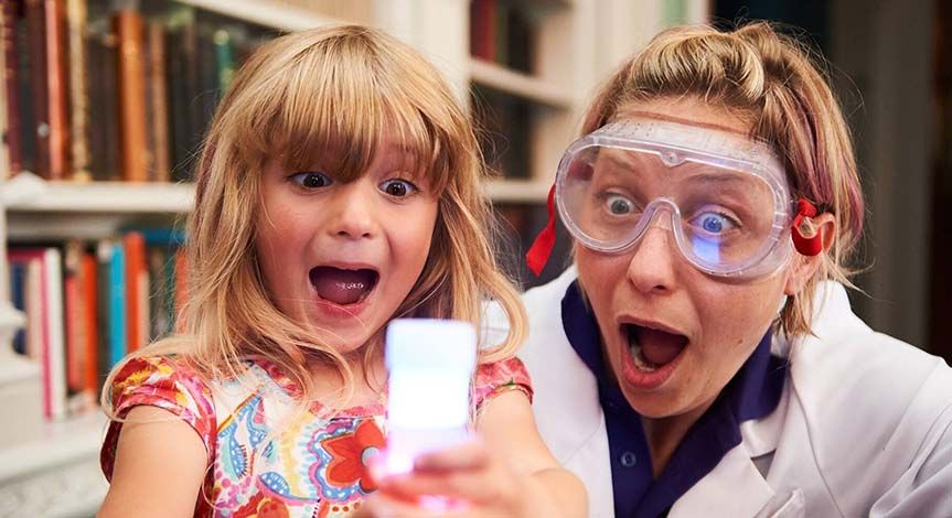 Excited girl and Mad Scientist looking at beaker filled with white liquid