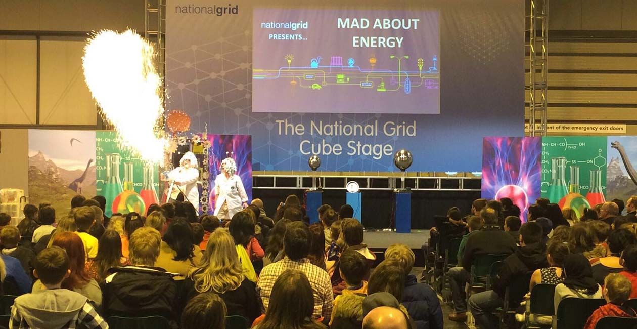 Mad Scientist blowing fire out of machine while kids look on at a mad science special event