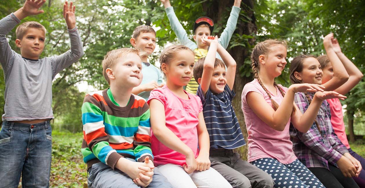 Group of positive children playing in the park sitting on the bench